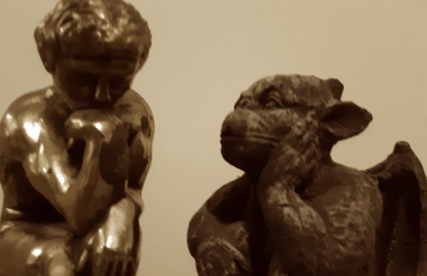 "The Thinker" bookend, short-haired figure with head resting on chin, in conversation with small gargoyle, winged creature with one hand resting on face
