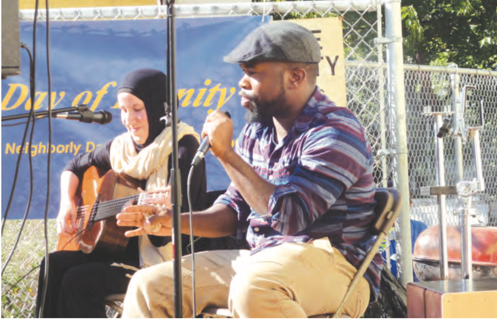 Lauren Schreiber, on guitar, and Muhammad Y. Oda, at the mic, perform together outside AIHM, then at 2315 Martin Luther King Jr Ave, SE, Oct 11, 2015.